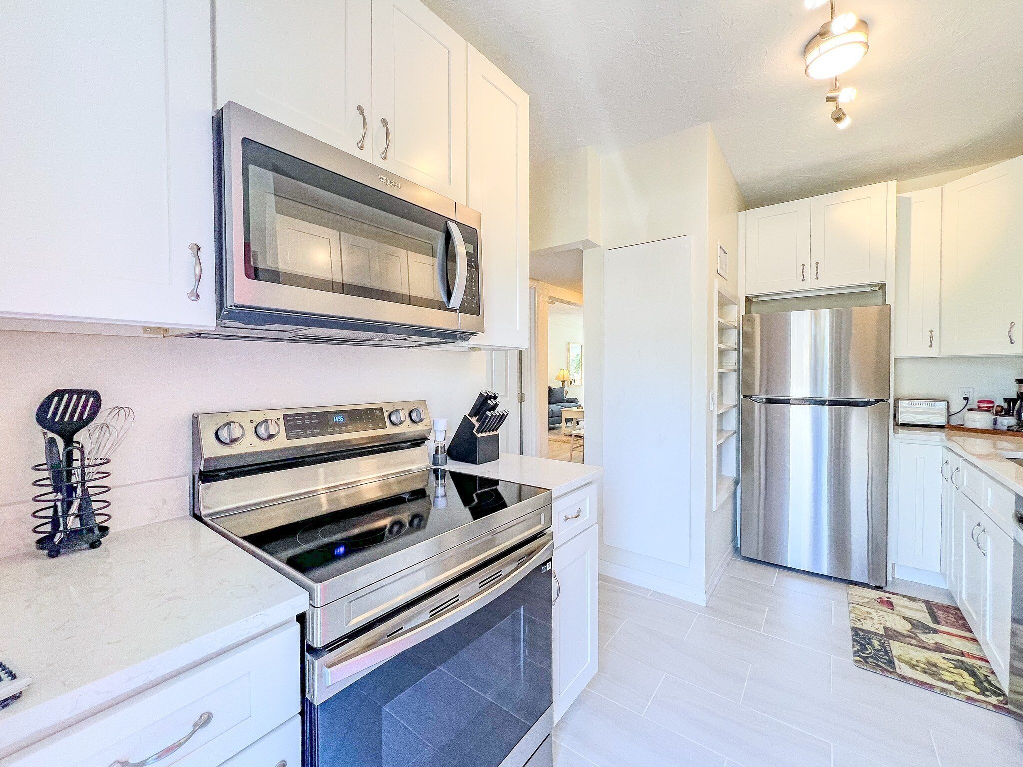A modern kitchen with stainless steel appliances, white cabinetry, and a visible microwave.