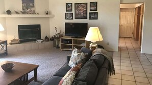 A living room with a sofa, a TV, a fireplace, and a hallway.