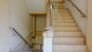 Eine Treppe mit Handlauf, hellbeigen Stufen und einer weißen Wand.