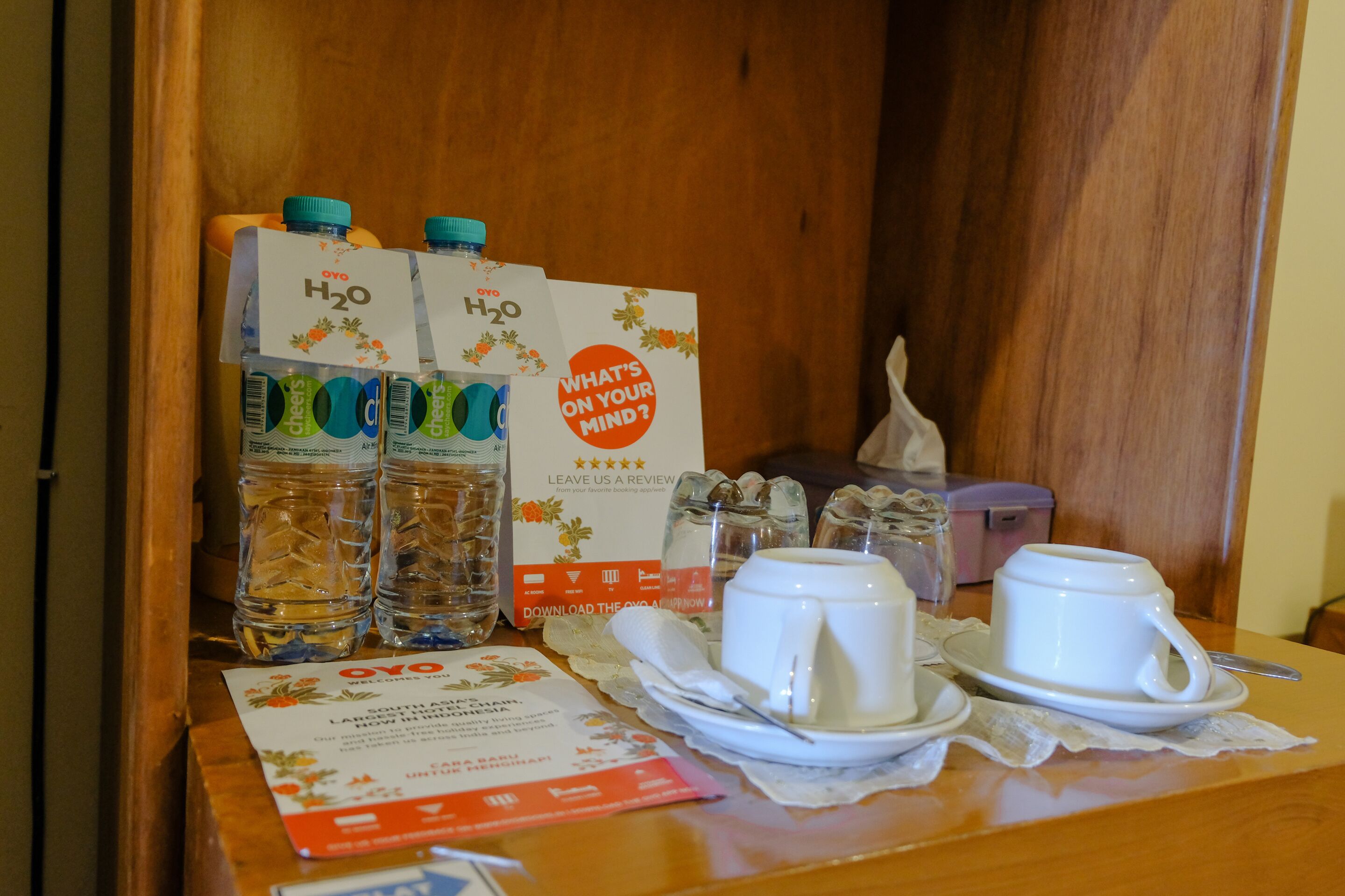A breakfast table with a coffee cup, sugar packets, a tissue box, and a sign asking for reviews.