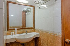 Un baño con un lavabo blanco, un espejo y una puerta de madera.