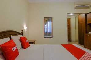 Una habitación de hotel con cama, mesita de noche, espejo y armario.