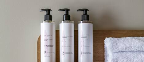 A shelf with three toiletry bottles and a white towel.