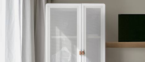 A bedroom with a bed, a wardrobe, a handbag, and a window with curtains.