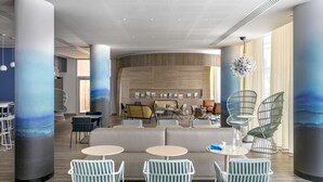 Un interior moderno con una zona de estar, mesas y una pared grande con diseño de paneles de madera.