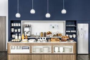 A buffet setup with various food items, utensils, and storage shelves. - OKKO Hotels Toulon Centre (Toulon)