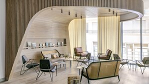 Un interior moderno con una pared curva de madera, un sofá y una zona de comedor con sillas y mesas.