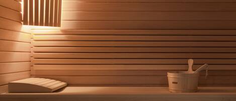 A wooden sauna with a bench, a wall-mounted light, and a bucket with a wooden spoon.