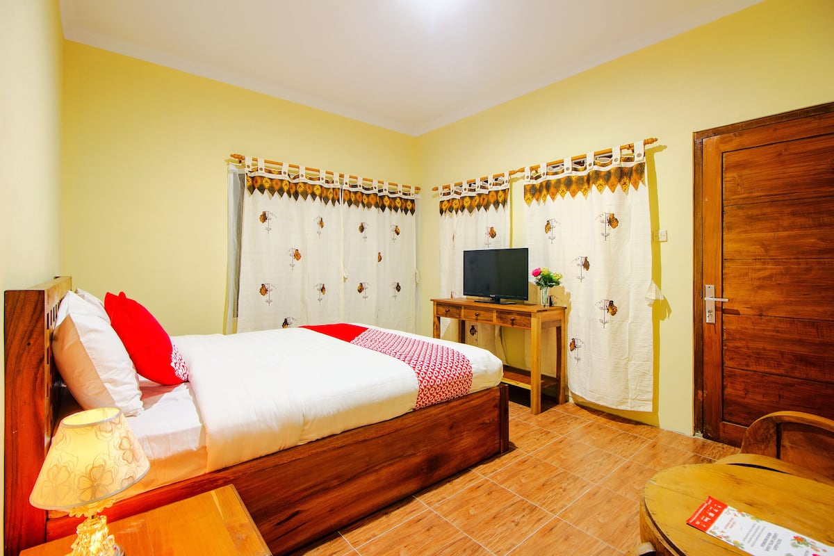 Ein Schlafzimmer mit einem Bett, einem Fernseher, einem Holztisch und einem Stuhl.