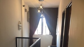 A narrow hallway with a black railing, a bench, and a window with curtains. - Comfortable Stay (George Town)
