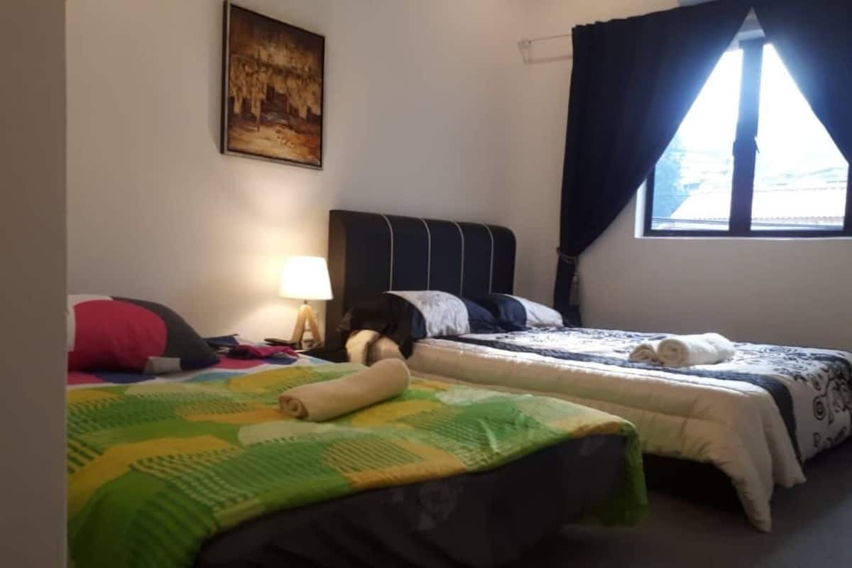 Una habitación de hotel con dos camas, una mesita de noche, una lámpara y un cuadro en la pared.