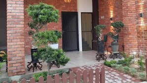 A brick building with a covered entrance, a sign advertising a comfortable stay, and potted plants around the entrance. - Comfortable Stay (George Town)