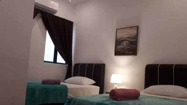 A hotel room with two beds, a window with curtains, a painting on the wall, and a lamp on the nightstand. - Comfortable Stay (George Town)