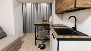 Une cuisine compacte dotée d’un plan de travail en bois, d’un évier noir et d’un petit coin repas avec une chaise.
