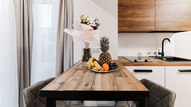 Une cuisine moderne avec un plan de travail en bois, un évier et un coin repas avec une table mise pour deux personnes.