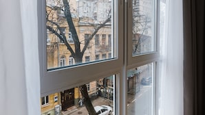 Une pièce dotée d’une grande fenêtre donnant sur une rue animée, avec des voitures et des immeubles.