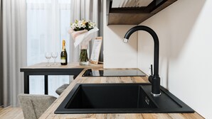 Une cuisine moderne dotée d’un évier noir, d’un plan de travail en bois et d’une hotte intégrée.