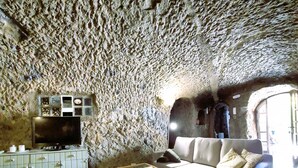 A cave-like interior with a sofa, coffee table, and cabinets. - El Mimo rural cave house (Artenara)