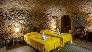 A room with two beds, each with a yellow bedspread and white towels, in a stone-walled interior. - El Mimo rural cave house (Artenara)