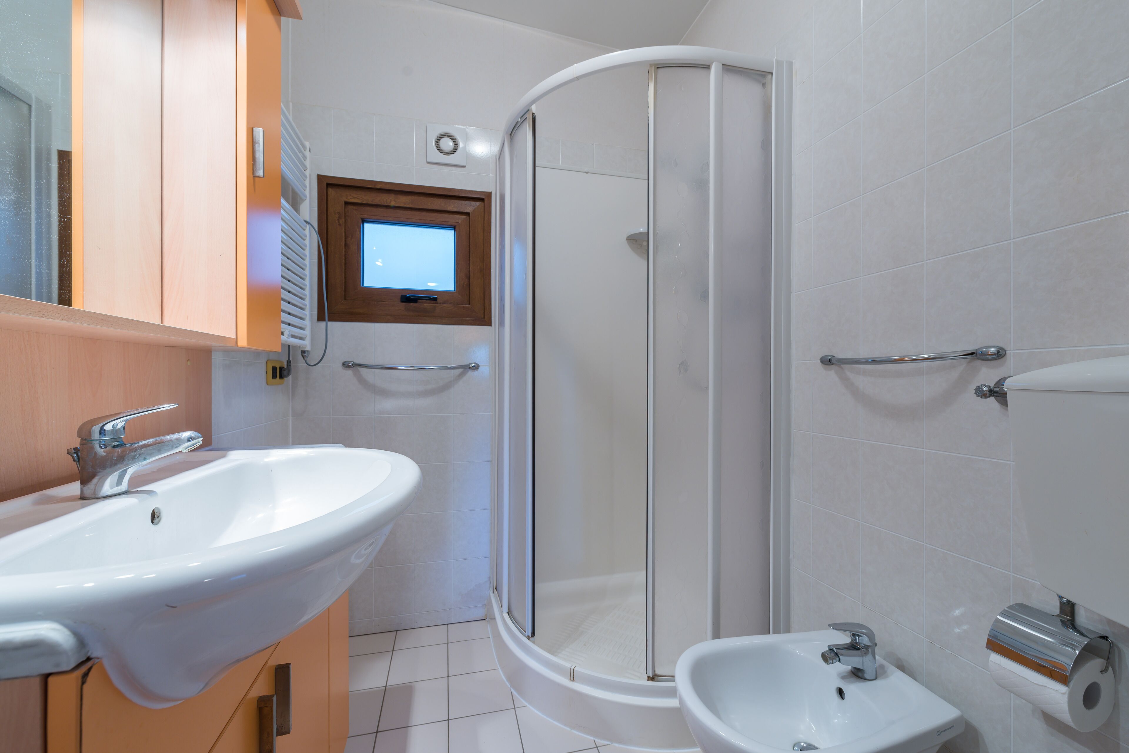 Ein Badezimmer mit weißem Waschbecken, einem kleinen Standbecken, einer Duschkabine und einer Toilette.