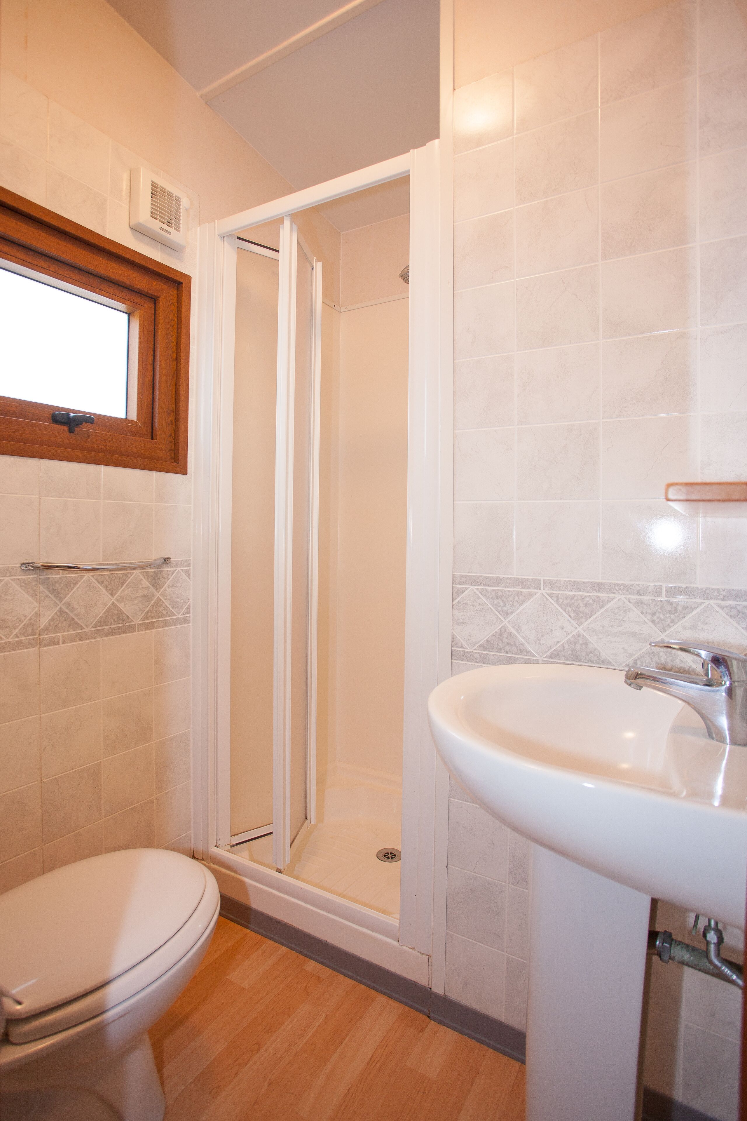 Un baño con inodoro, lavamanos y zona de ducha.
