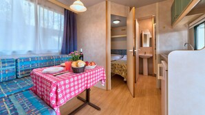 Una habitación compacta con kitchenette, un comedor con mesa para dos, un sofá y una cama.