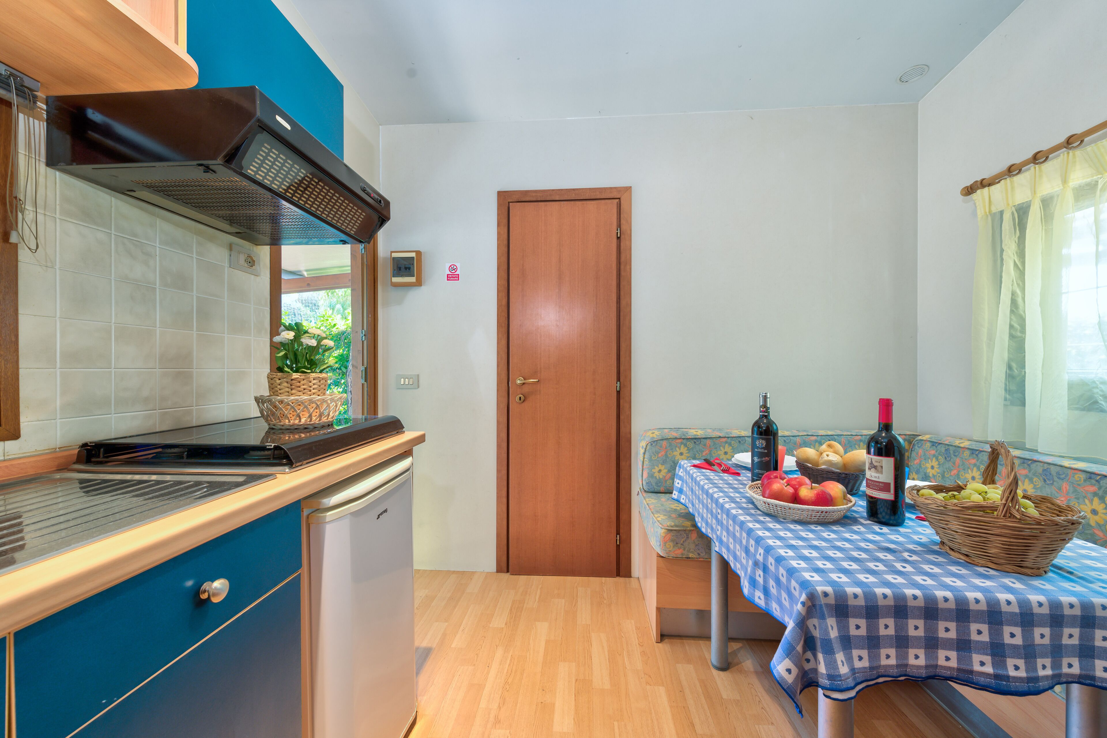 Eine kleine Küche mit Einbauherd, Spüle und Fenster mit Blick auf Grünflächen.