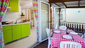 Una cocina con armarios verdes y una zona de comedor con mantel a cuadros.