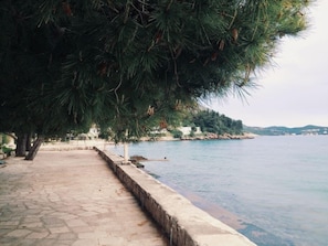 A paved waterfront walkway with a stone border, leading to a body of water.