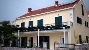 A two-story building with a stone facade, green shutters, and a red-tiled roof. - Vila Morska Sirena (Zupa dubrovacka)