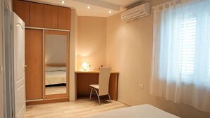 A bedroom with a bed, a desk, and a chair. There is a wardrobe and an air conditioning unit on the wall. - Vila Morska Sirena (Zupa dubrovacka)