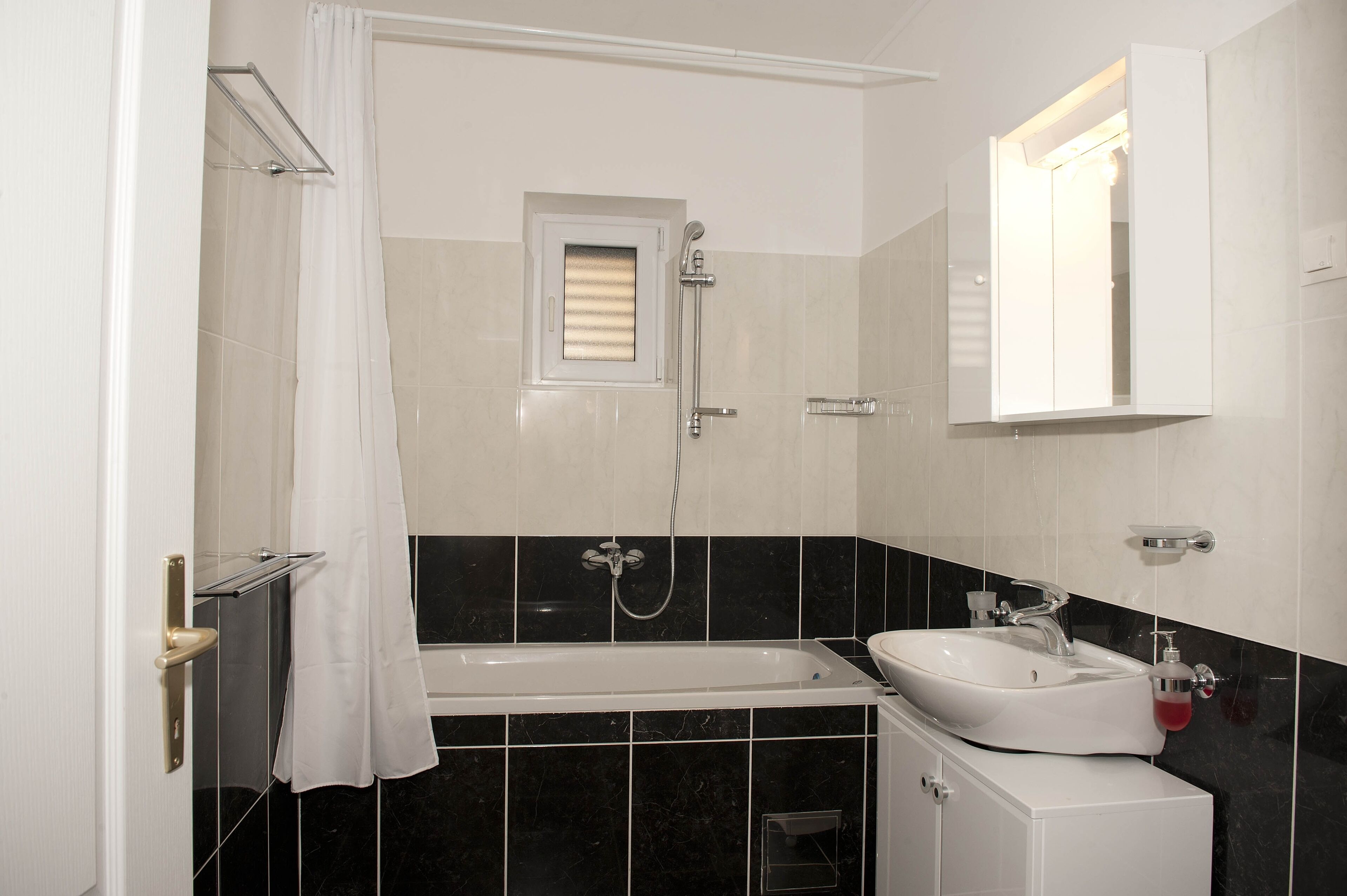 A bathroom with a bathtub, a sink, a mirror, and a shower.