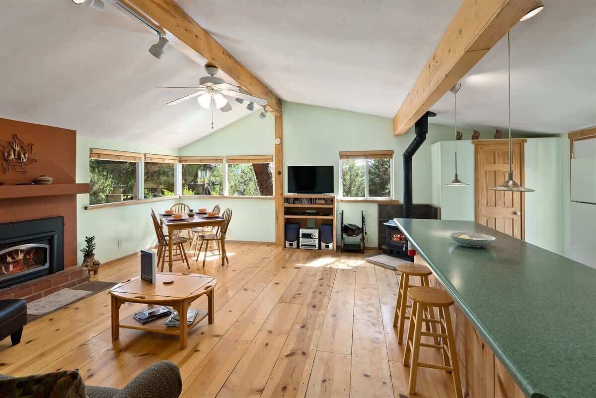 A spacious living area with a fireplace, wooden flooring, a dining table, and a kitchen with a large island.