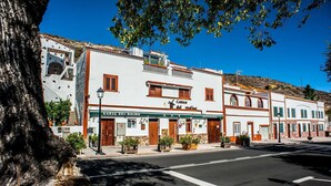 A street view with a building labeled "Cueva del Molino" featuring a traditional facade, a clear sky, and a tree in the foreground.