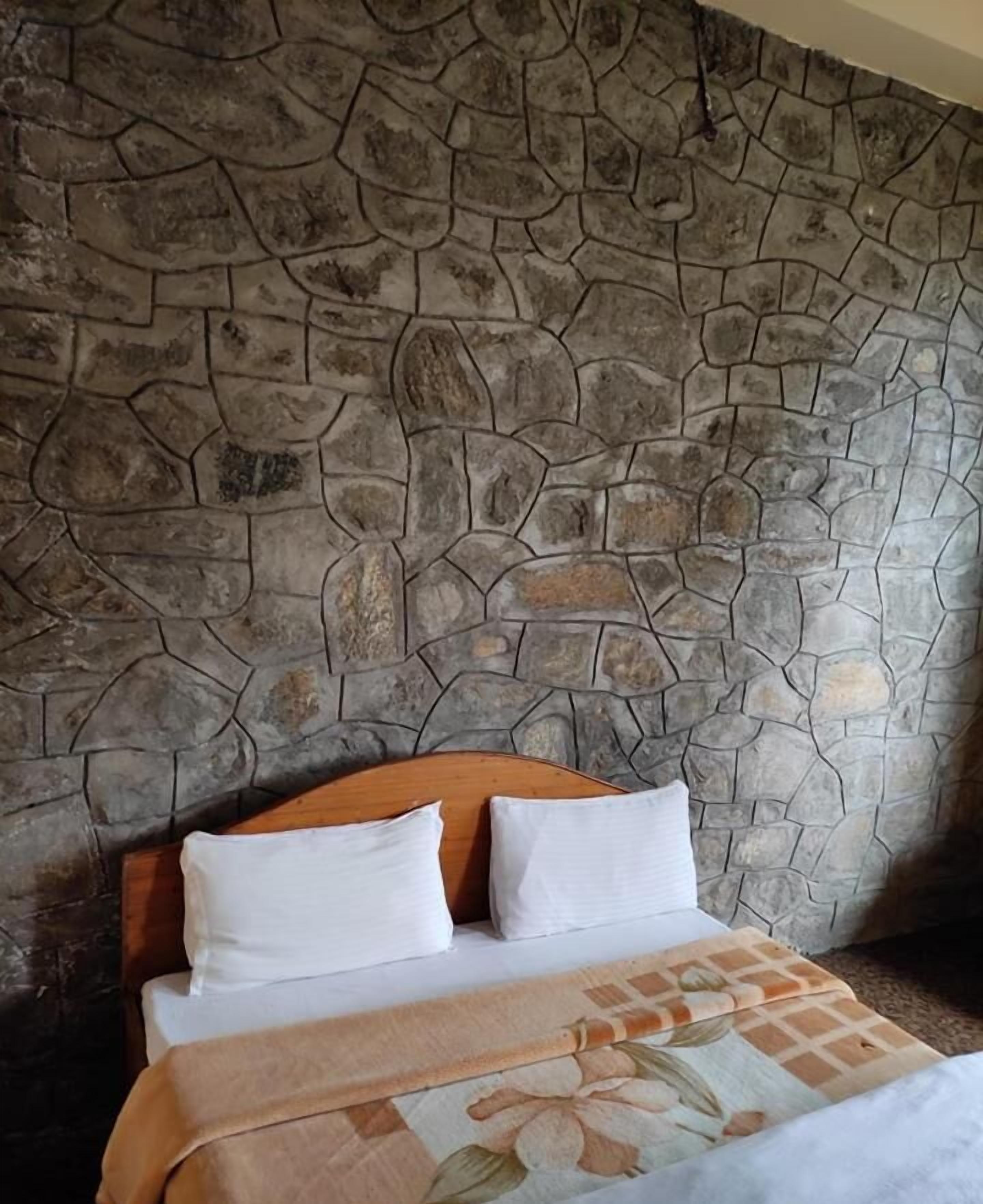 A bed with a wooden headboard, white pillows, and a floral-patterned bedspread.