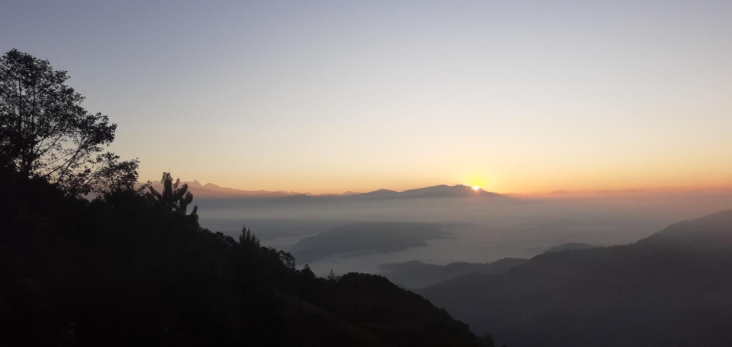 A mountainous landscape with a sunrise or sunset, featuring a clear sky and distant mountains.