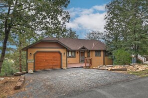 A single-story house with a brown garage door, a front porch, and a stone driveway.