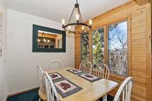 A dining area with a wooden table, white chairs, and a chandelier.