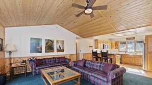 L’intérieur chaleureux d’un chalet avec un plafond en bois, un coin repas et une cuisine.