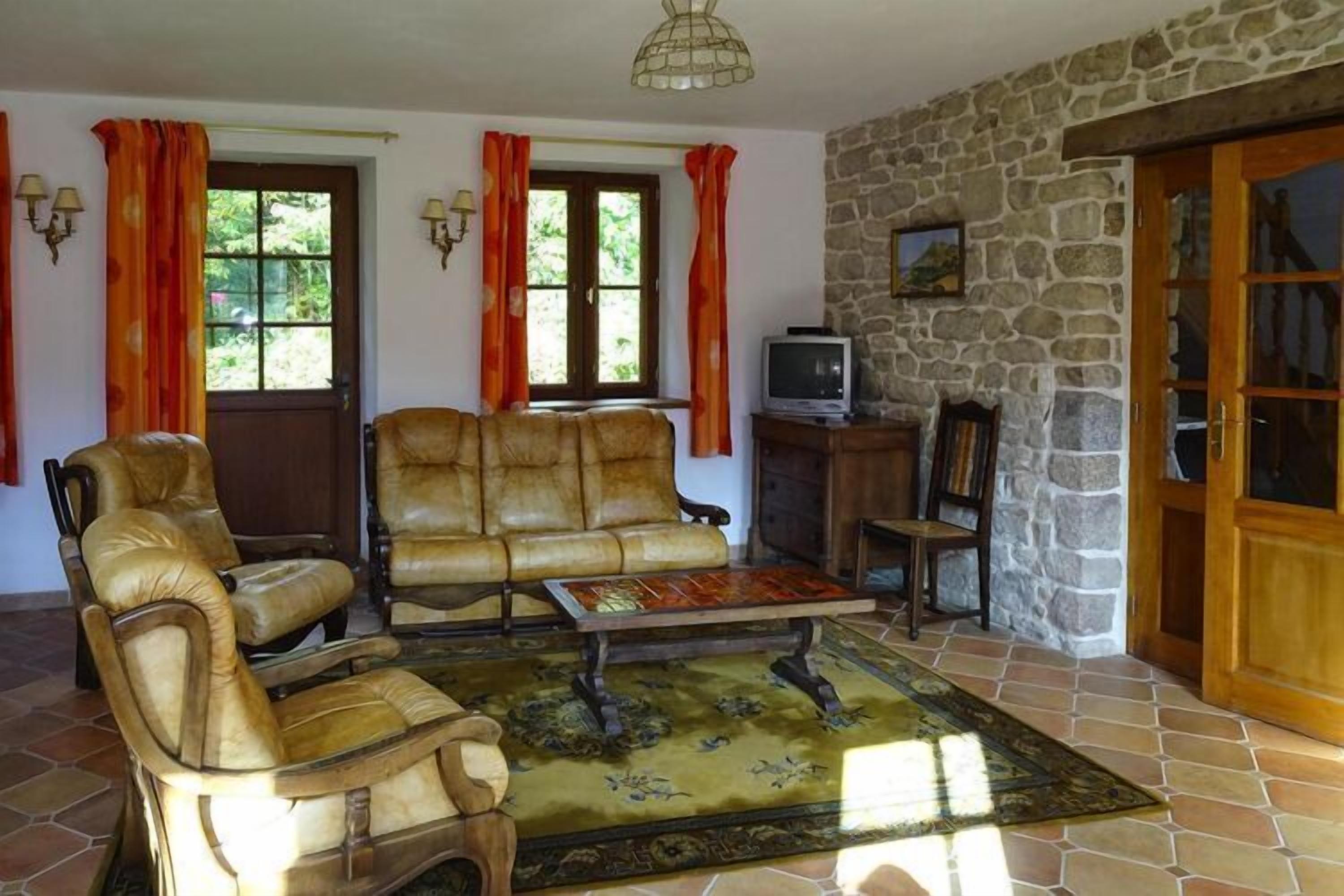 Una sala de estar acogedora con muebles de cuero, pared de piedra y televisor.