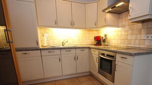 A kitchen with white cabinets, a stainless steel oven, and a coffee maker. - Reihenhaus, St. Peter - Ording (St. Peter-Ording)