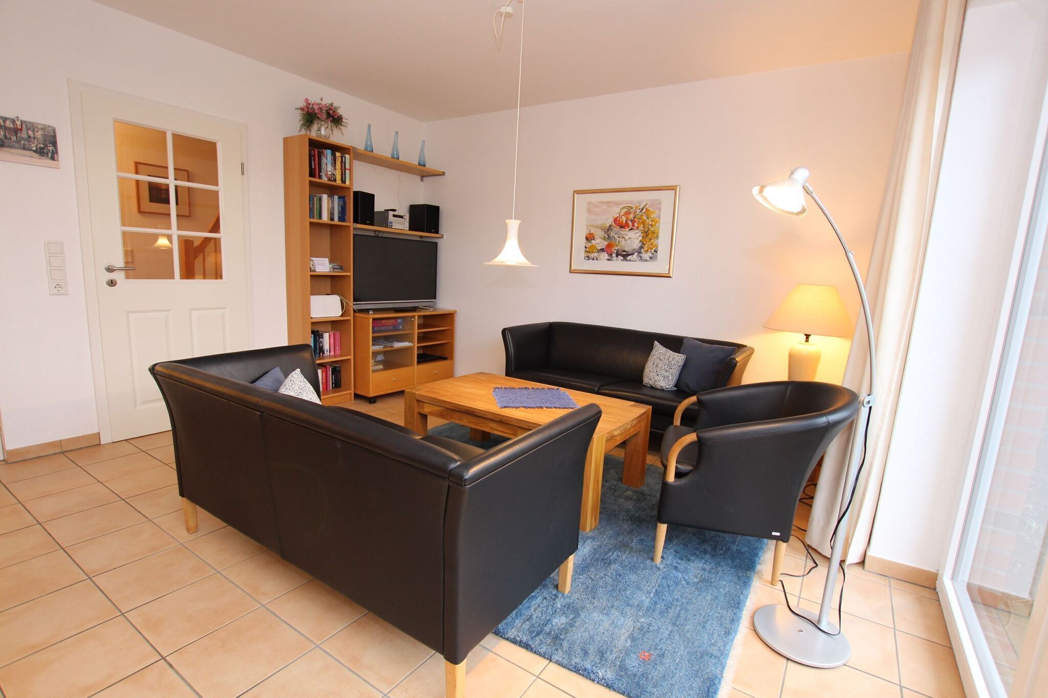 Een woonkamer met een bank, een salontafel, een televisie, een boekenkast en een lamp.