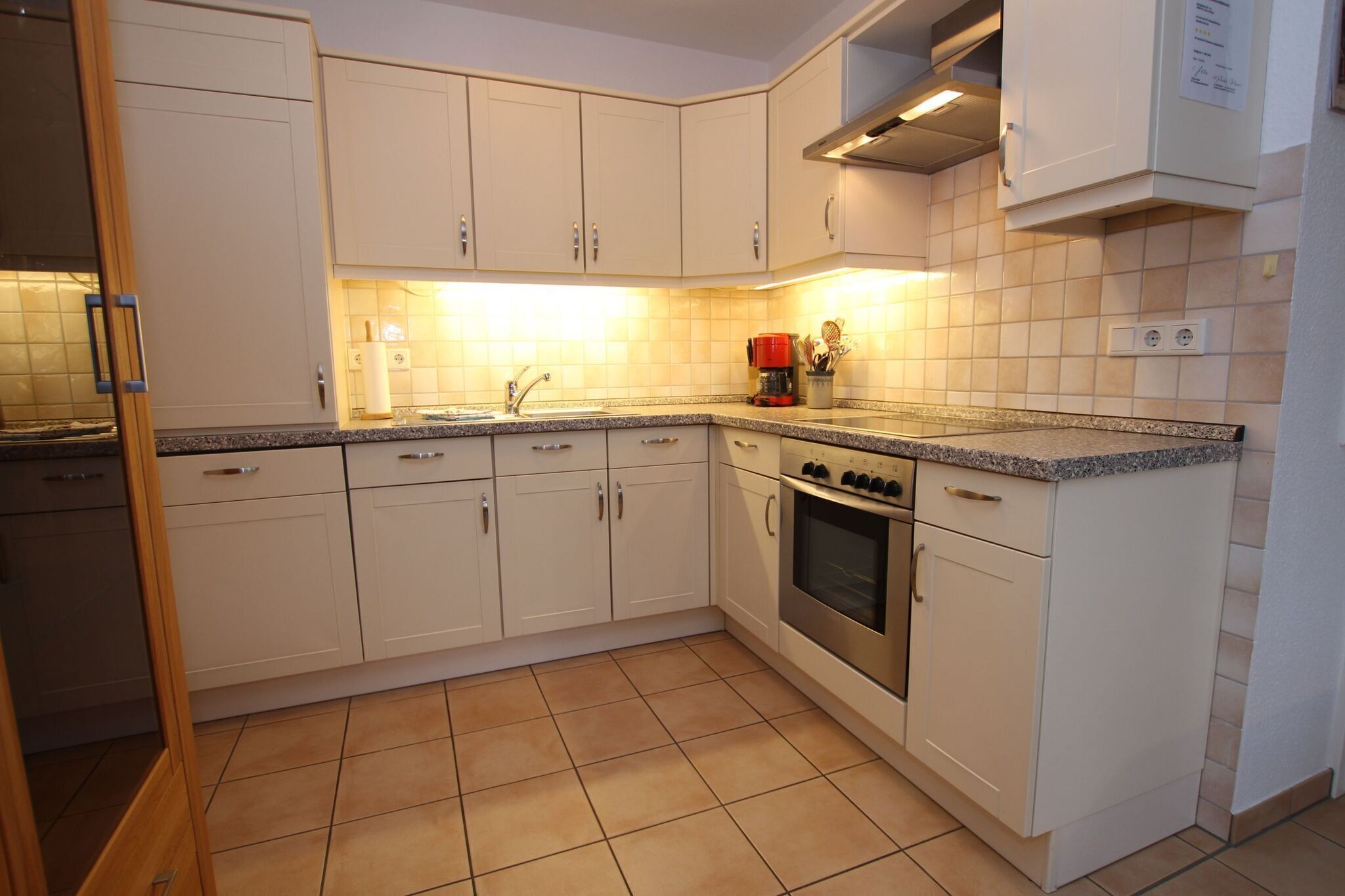 A kitchen with white cabinets, a granite countertop, a stainless steel oven, and a coffee maker.