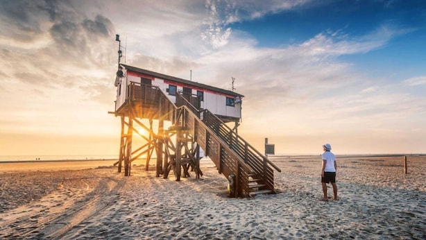 A wooden pier with a lifeguard tower at sunset.