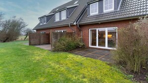 A two-story house with a sloped roof, a brick exterior, and a glass door entrance.