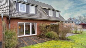 A two-story house with a brick facade, a tiled roof, and a front door with glass panels.