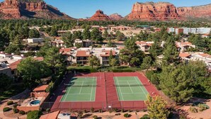 Zona residencial con dos canchas de tenis, rodeada de casas y montañas.