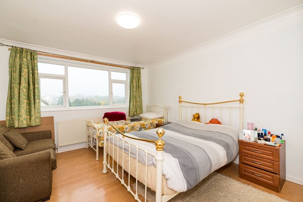 Une chambre à coucher avec un lit, une commode, une chaise et une fenêtre.