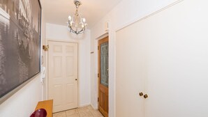 A hallway with a wooden bench, a white door, and a wall-mounted picture.