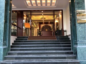 Ein Hotel mit Eingangsbereich, Marmorstufen, einer Rezeption und einem Kronleuchter.
